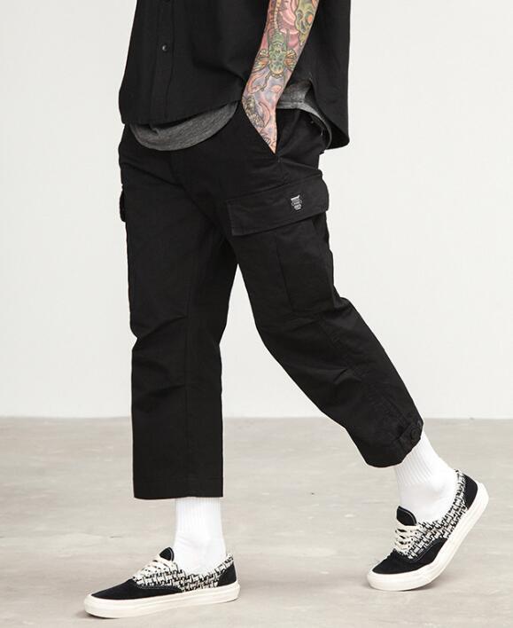 mens wearing camouflage jogger pants with elastic waist and side buttons, styled for a casual streetwear look.