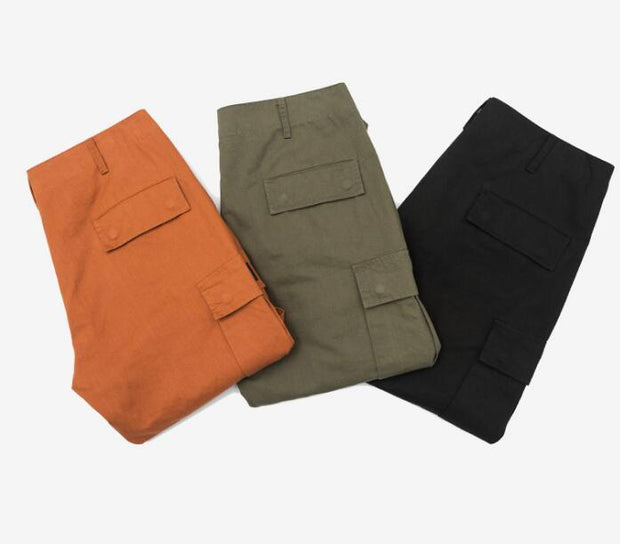 mens wearing camouflage jogger pants with elastic waist and side buttons, styled for a casual streetwear look.