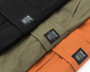 mens wearing camouflage jogger pants with elastic waist and side buttons, styled for a casual streetwear look.