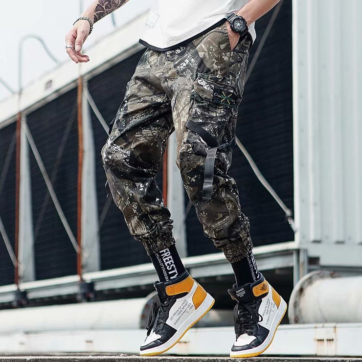 Hip Hop jogger pants in camouflage design, featuring elastic cuffs and a relaxed fit, styled with sporty sneakers.
